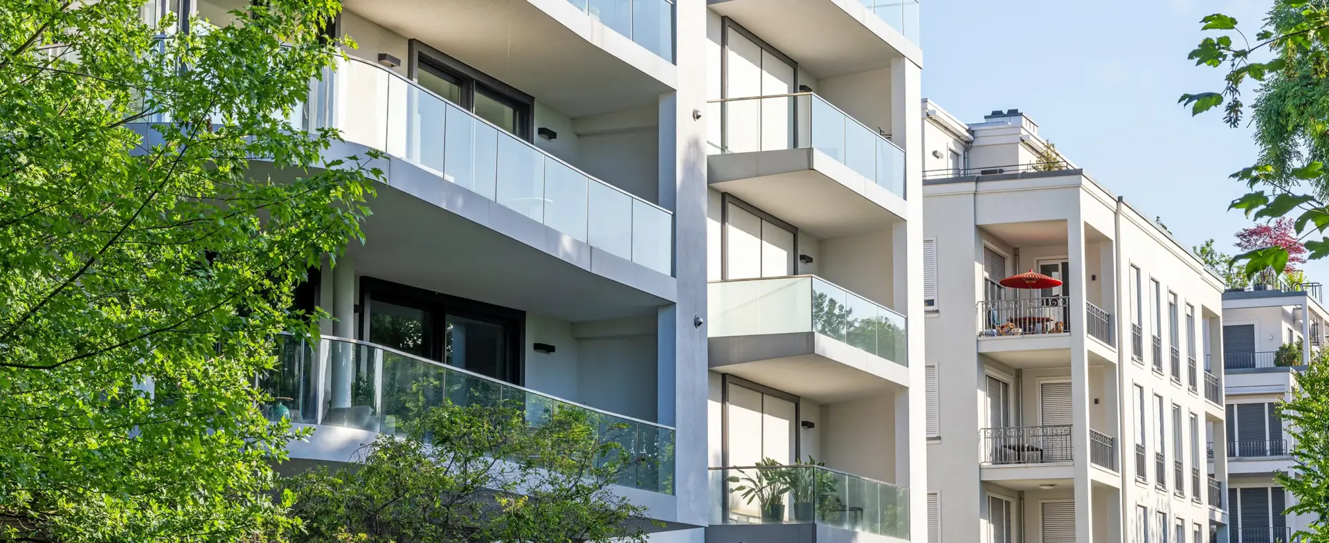 Fassade eines modernen Wohnblocks mit Balkonen und Grünanalage