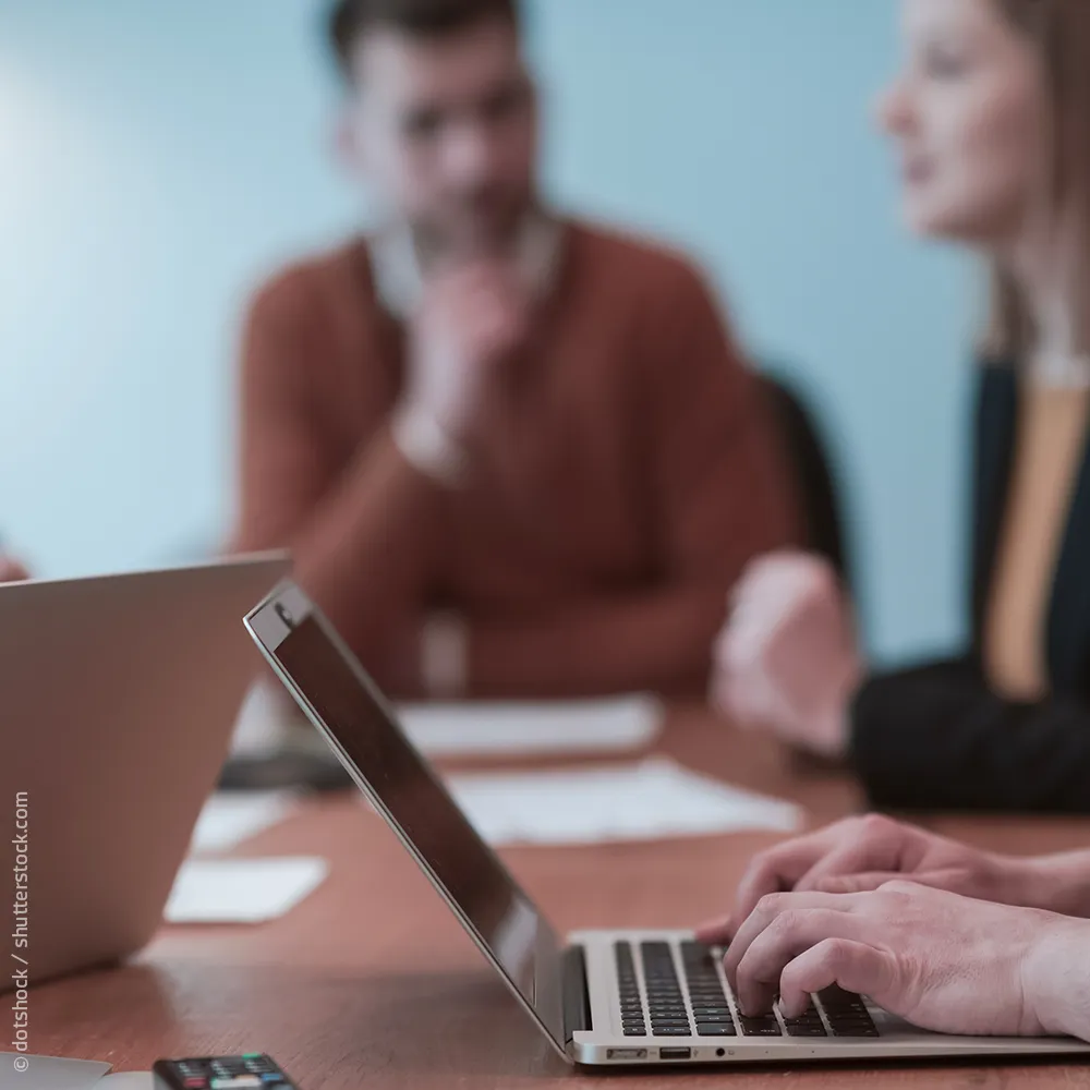 Team Meeting mit Laptop im Vordergrund
